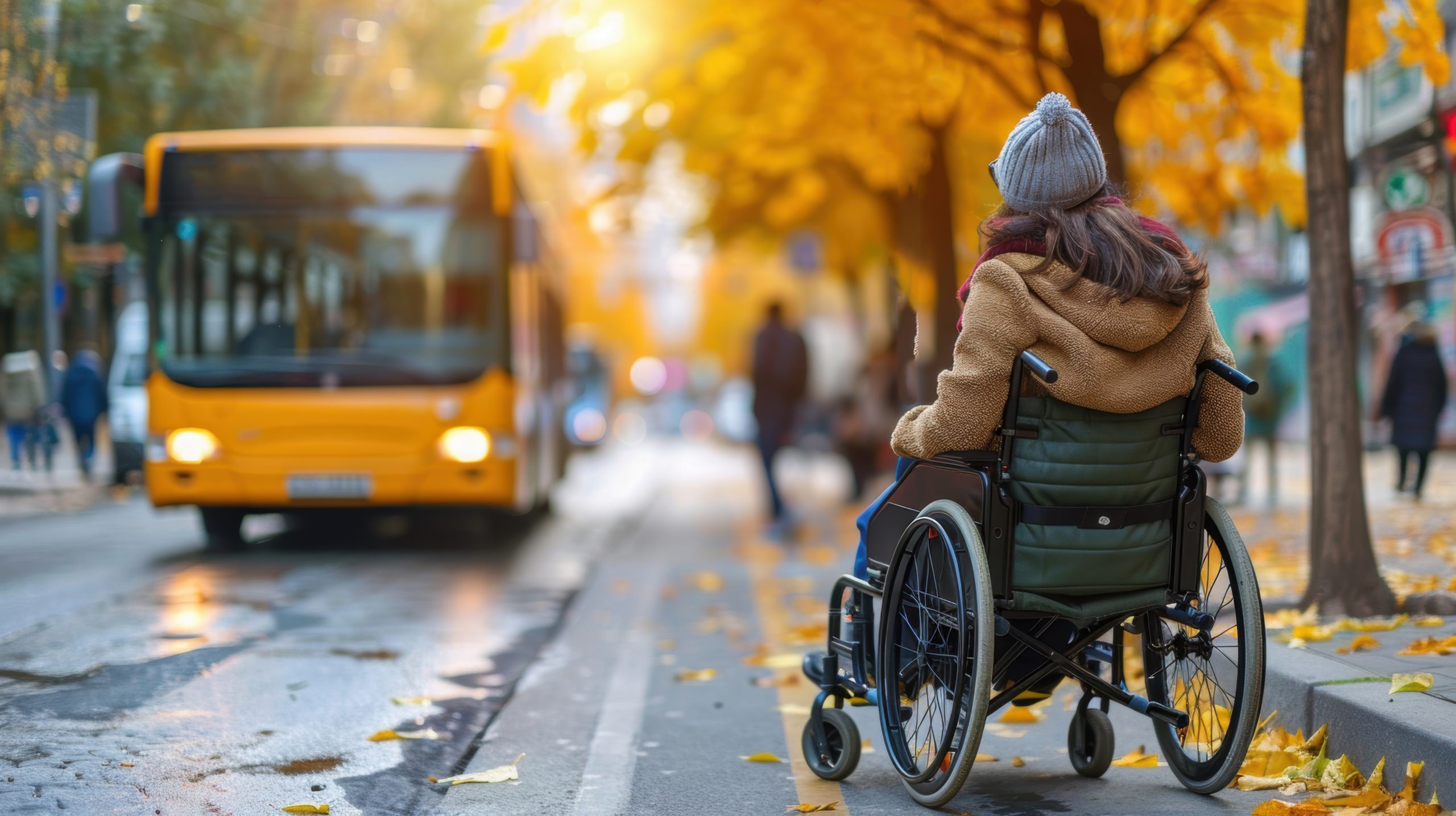 Personne en fauteuil roulant attendant le bus par une journée d'automne, mettant en évidence l'accessibilité et les transports publics en milieu urbain. Une personne en situation de handicap attend le bus