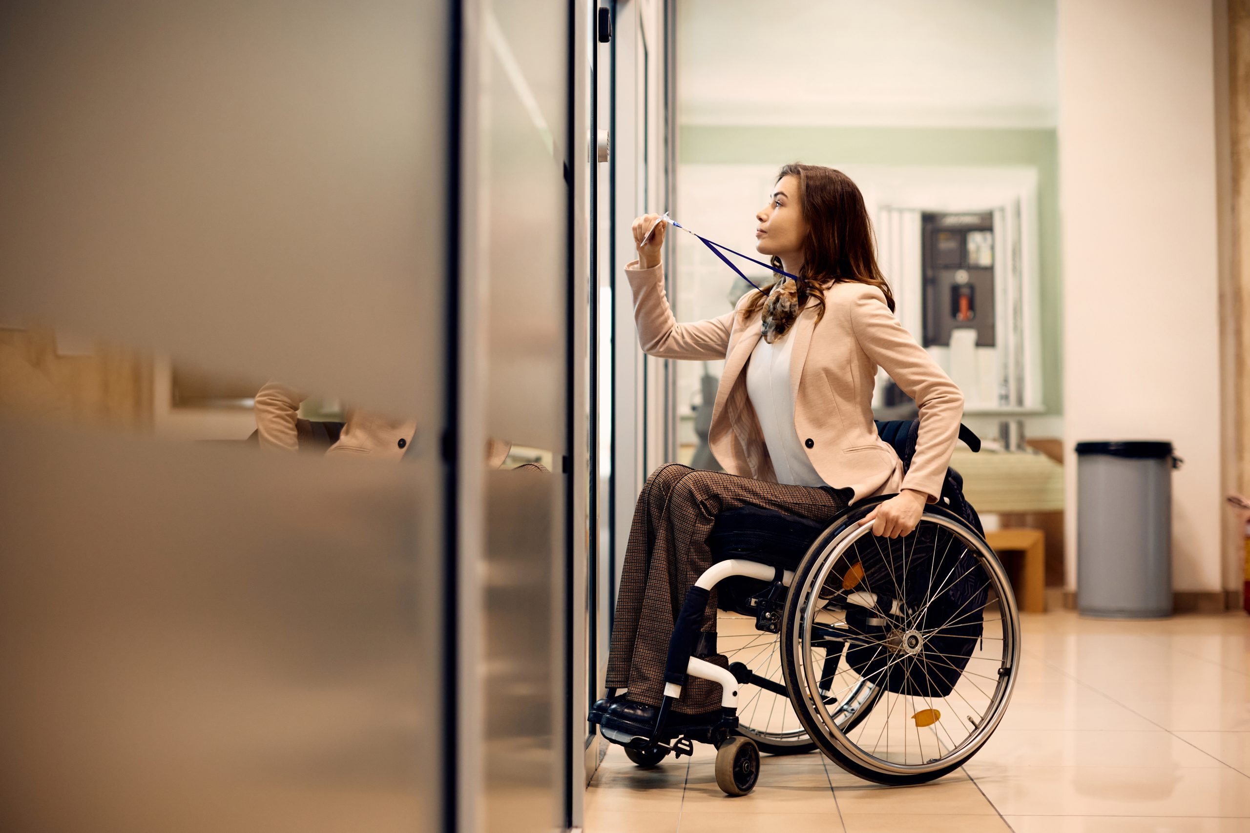 Une jeune femme d'affaires handicapée utilise une carte d'accès pour entrer dans le bureau. Il y a une jeune femme en situation de handicap qui badge sa porte de bureau