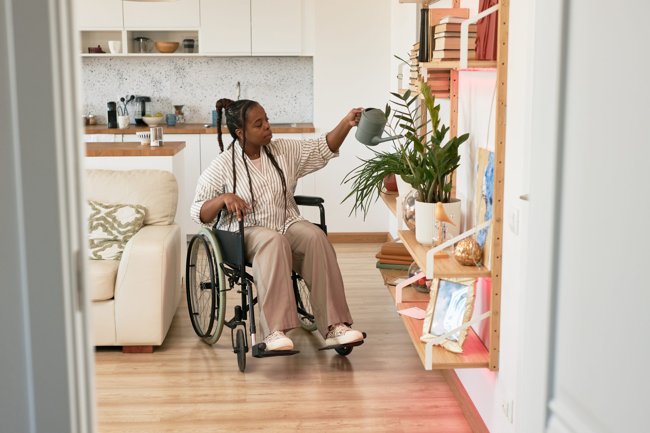 Arroser les plantes dans un appartement moderne accessible C'est une jeune femme en situation de handicap,