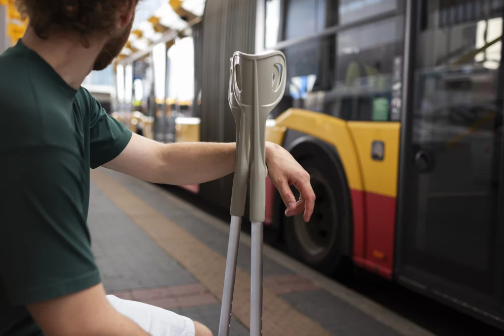 Personne-en-béquilles-qui-attend C'est un homme qui attend le bus à un arrêt de bus et il est en situation de handicap